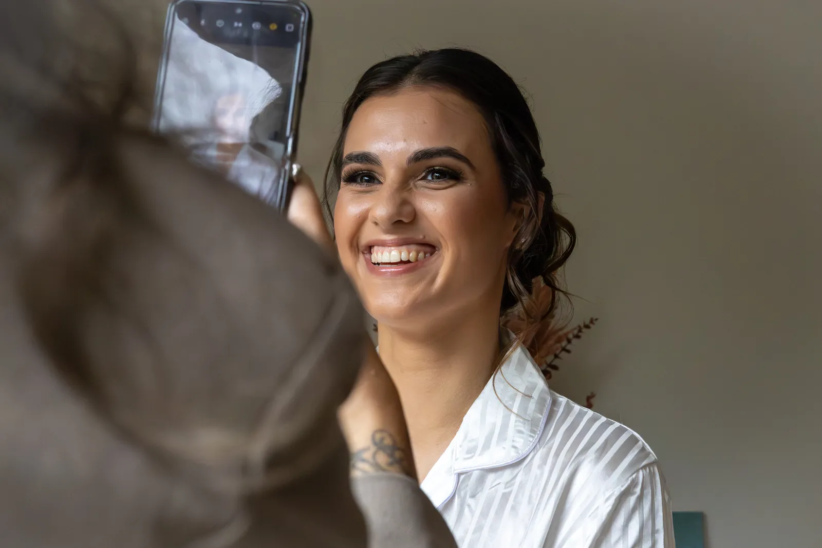 Alyssa lacht terwijl haar make-up wordt gedaan, op de ochtend van de bruiloft