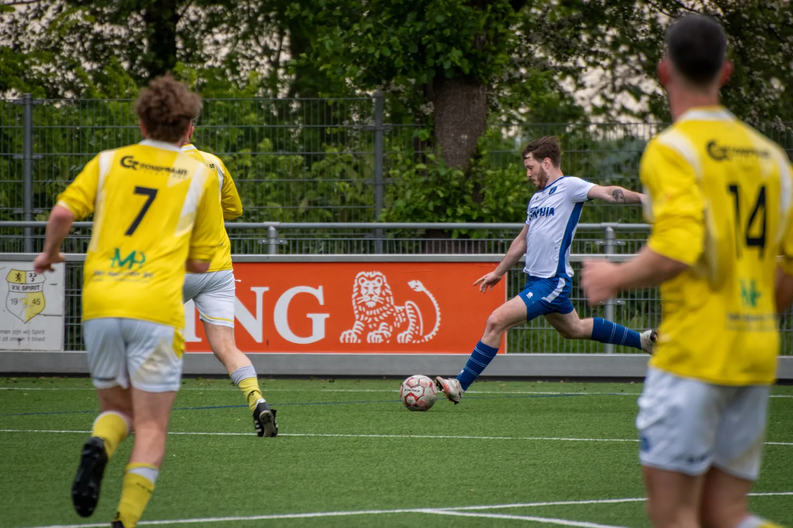 Speler van CVV Zwervers haalt uit tussen twee verdedigers van VV Spirit