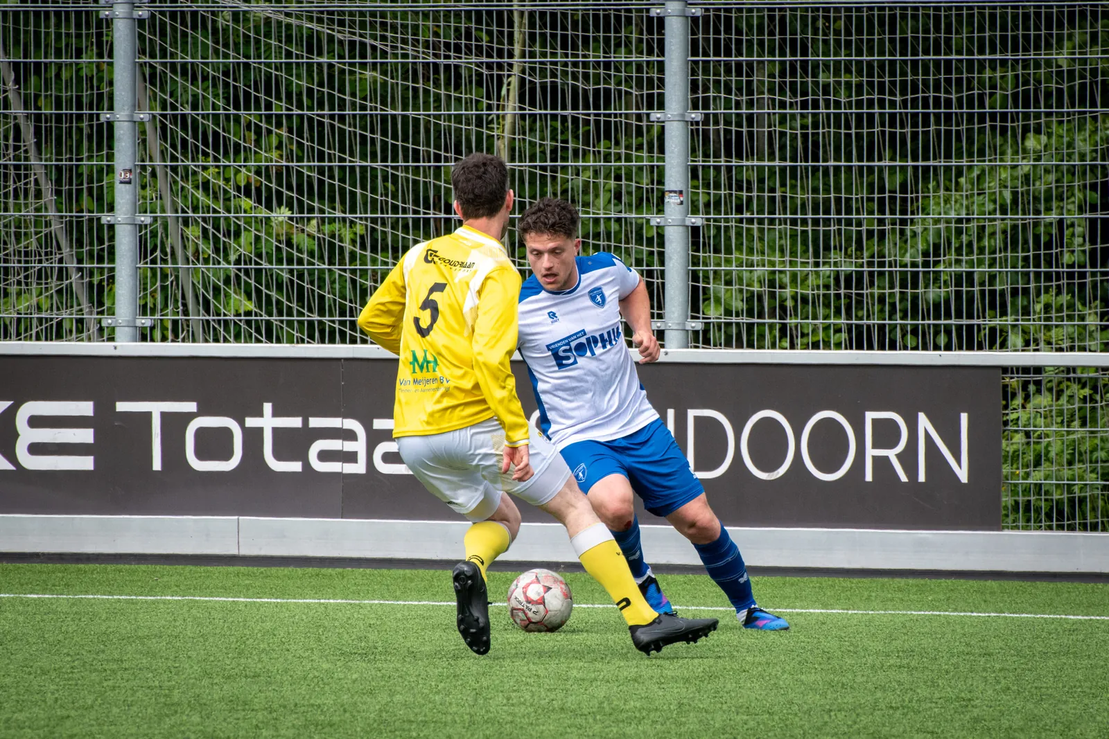 Duel om de bal tussen CVV Zwervers en VV Spirit langs de reclameborden